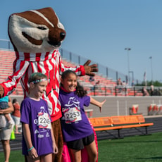 Girls on the Run participants standing on both sides of Bucky the Badger mascot
