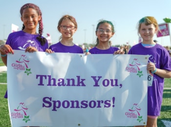 Four Girls on the Run participants holding a poster that says Thank You Sponsors