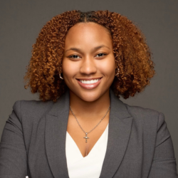 Professional headshot of a smiling woman in a grey blazer