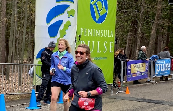 Photo of Beth holding up her medal after completing the 2023 Door County Half Marathon! 